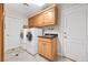 Bright laundry room with full-size washer and dryer, sink, and ample cabinet space for storage at 7450 Via Olivero Ave, Las Vegas, NV 89117