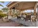 Covered outdoor living area with slate flooring, comfortable seating, and view of landscaped backyard and putting green at 7450 Via Olivero Ave, Las Vegas, NV 89117