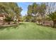 Putting green in backyard, with mature trees, lush landscaping, and stone accents at 7450 Via Olivero Ave, Las Vegas, NV 89117