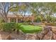 Beautiful backyard putting green featuring mature trees, desert landscaping and covered structure at 7450 Via Olivero Ave, Las Vegas, NV 89117