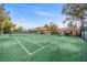 Well-maintained tennis court surrounded by lush greenery and blue skies at 7450 Via Olivero Ave, Las Vegas, NV 89117