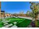 Landscaped backyard featuring artificial turf, stone pathways, and a relaxing seating area at 9016 Skye Canyon Ranch St, Las Vegas, NV 89166