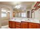 Ensuite bathroom with double sinks, wood cabinets, a large mirror and open doorway to bedroom at 9328 Freedom Heights Ave, Las Vegas, NV 89149