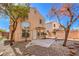 Rear exterior view of a two-story home with a patio, mature trees, and desert-friendly landscaping at 9328 Freedom Heights Ave, Las Vegas, NV 89149