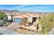 Tan house with blue garage door, desert landscaping, and mountain views at 1290 El Solindo Ln, Henderson, NV 89002