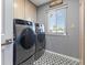 Convenient laundry room boasts sleek gray washer and dryer set, complemented by stylish black and white patterned flooring at 321 E Middleton Dr, Henderson, NV 89015