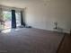 Expansive living room featuring plush carpeting, sliding glass doors to a covered patio, and neutral walls at 5490 Shodall Cir, Las Vegas, NV 89120