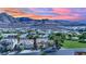 An aerial view of a sunset over the neighborhood with mountain views and a green common area at 725 Pacific Cascades Dr, Henderson, NV 89012