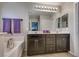 Bathroom featuring dual vanities, modern lighting, and a separate tub with stylish fixtures at 8736 Summoners Ct, Las Vegas, NV 89139