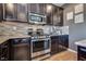 Close up of the kitchen features stainless steel appliances, light countertops, tile backsplash, and dark cabinetry at 8736 Summoners Ct, Las Vegas, NV 89139