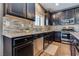 Kitchen featuring stainless steel appliances, tile backsplash, wood floors and dark cabinetry at 8736 Summoners Ct, Las Vegas, NV 89139
