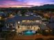 Dusk aerial shot of an estate with a pool, covered patio, backyard, and colorful mountain views at 10000 Cresent Mesa Ln, Las Vegas, NV 89145