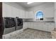 Laundry room featuring white cabinetry, a large window, and modern washer and dryer units at 10000 Cresent Mesa Ln, Las Vegas, NV 89145