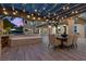 Beautifully designed outdoor patio with dining area, fireplace, and overhead string lights for evening relaxation at 10000 Cresent Mesa Ln, Las Vegas, NV 89145