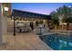 Inviting backyard swimming pool and lounge area with lights, basketball hoop, and a covered dining space at 10000 Cresent Mesa Ln, Las Vegas, NV 89145