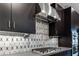 Close up of range, hood and backsplash in modern kitchen with sleek dark cabinetry at 4269 Solace St # 0, Las Vegas, NV 89135