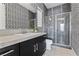 Modern bathroom featuring a glass-enclosed shower, sleek black vanity, and unique patterned wallpaper at 64 Bella Lago Ave, Henderson, NV 89011