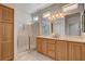 Main bathroom with double sinks, shower, and light wood cabinets at 10228 Questa Sera Ct, Las Vegas, NV 89135