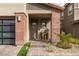 Inviting front entrance showcasing a modern door, brick accents, and lush landscaping at 10936 White Alder Pl, Las Vegas, NV 89138