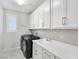 Bright laundry room with white cabinets, washer, dryer, and utility sink at 12846 Ringrose St, Las Vegas, NV 89141