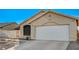 Tan home featuring a two-car garage and a well maintained lawn at 2177 Bridle Wreath Ln, Las Vegas, NV 89156