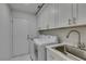 Laundry room features side by side washer and dryer, utility sink, white cabinets and a door to the exterior at 2604 Sun Reef Rd, Las Vegas, NV 89128