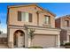 Two-story house with tan exterior, arched entryway, and landscaping at 10636 Tulip Valley Rd, Las Vegas, NV 89179