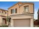 Two-story house with tan exterior, brown garage door, and landscaping at 10636 Tulip Valley Rd, Las Vegas, NV 89179