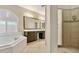 Elegant bathroom featuring a soaking tub, tiled shower, and a large mirror with ample lighting at 2026 Dakota Lodge Ave, Las Vegas, NV 89123