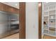 Walk-in pantry with custom shelving, a stainless steel refrigerator, and wood-paneled door at 506 Overlook Rim Dr, Henderson, NV 89012