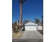 White two-car garage with solar panels on the roof, and a palm tree nearby at 6136 Evensail Dr, Las Vegas, NV 89156