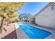 Long rectangular pool in backyard with surrounding landscaping and string lights at 6185 N Conquistador St, Las Vegas, NV 89149