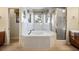 Bathroom featuring a soaking tub with decorative tile work, surrounded by windows and a glass shower at 8365 Hauck St, Las Vegas, NV 89139