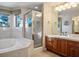 Bathroom featuring a soaking tub, marble counters, dark wood cabinets, and a glass shower enclosure at 8365 Hauck St, Las Vegas, NV 89139