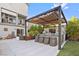 Outdoor kitchen with grill, bar seating, pergola, TV, and beautiful landscaping at 8620 Grove Mill Ct, Las Vegas, NV 89139