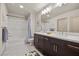 Bright bathroom with double vanity, tiled floor, tub, and shower combo with modern fixtures at 8620 Grove Mill Ct, Las Vegas, NV 89139