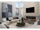 Bright, open living room featuring large windows, a stone fireplace, and modern curved sofas at 4377 Cameron Brook Ct, Las Vegas, NV 89129