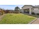 Large backyard with a well-maintained lawn, covered patio, and mature landscaping at 7520 Darian Jane St, Las Vegas, NV 89149