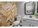 Powder room featuring a herringbone accent wall, a stylish mirror, and a modern toilet and vanity at 7520 Darian Jane St, Las Vegas, NV 89149