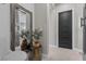 Bright hallway featuring a decorative mirror, a modern black door, and neutral-toned walls at 7520 Darian Jane St, Las Vegas, NV 89149