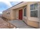 View of front entrance with red door, beige walls, a window, and well-manicured landscaping at 1069 Appleblossom Time Ave, North Las Vegas, NV 89031