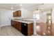 Open kitchen with wood cabinets, tile floors, and black dishwasher with bar top looking into the living room at 1069 Appleblossom Time Ave, North Las Vegas, NV 89031