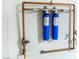Wall-mounted plumbing system with copper pipes and blue water filters at 1069 Appleblossom Time Ave, North Las Vegas, NV 89031