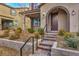 Charming home featuring a landscaped front yard, tiled roof, and covered entry with an arched doorway and brick walkway at 2436 Padulle Pl, Henderson, NV 89044