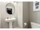 Small bathroom with pedestal sink, toilet, and round mirror at 4924 Conglobate St, Las Vegas, NV 89122