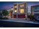 Contemporary two-story home with a stone facade, red garage doors, and modern landscaping at dusk at 6276 Olde Lockford Ct, Las Vegas, NV 89139