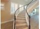 Elegant curved staircase with wood steps and dark handrail illuminated by natural light at 927 Via Canale Dr, Henderson, NV 89011