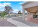 Covered patio with brick flooring overlooks a gravel yard and green space with mature landscaping at 9609 Eagle Valley Dr, Las Vegas, NV 89134