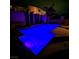 Inviting backyard pool illuminated with vibrant blue lighting surrounded by a privacy wall and a paved deck at 1136 Buckhorn Cove St, Henderson, NV 89011