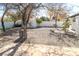 The backyard has gravel area, privacy fence, mature trees, a trash can and a small shed at 1403 5Th Pl, Las Vegas, NV 89104